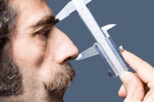 Close up photo of adult man nose measured with a vernier caliper. Profile view is shot. Isolated with clipping path. Shot in studio with a full frame DSLR camera and a macro lens.