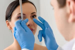 A doctor examining the results of a woman's nose surgery