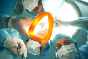  Low angle of professional surgeons giving to patient a general anesthetic before an operation. They are holding the equipment and surgical instruments