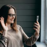 Happy brunette woman in glasses making facetime video calling