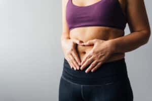 Woman holding hands in heart shape over her tummy.