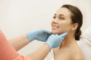 Doctor looking at woman’s glowing, youthful skin after getting dermal fillers.