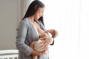 New mother with large breasts nurses her young baby. Her implants haven’t interfered with lactation