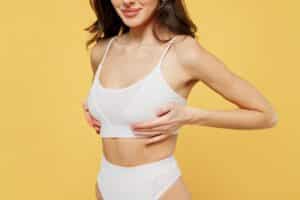 Woman in underwear and bra holding her breasts and considering breast lift or breast augmentation