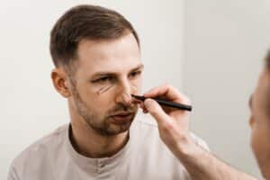 Plastic surgeon marking up man's nose to prepare for rhinoplasty