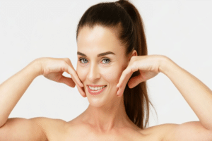 Woman lifting cheeks with hands, showing youthful, lifted appearance after non-surgical treatment with injectables and threads