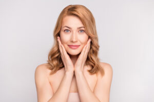 Woman touching her cheeks to highlight smooth facial contours and youthful volume.
