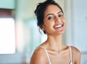 Smiling woman with smooth neck and décolletage skin, areas commonly treated with Restylane Skinboosters.